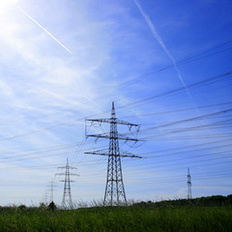 Auf dem Foto sind Strommasten vor blauem Himmel zu sehen.