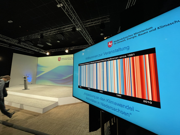 Ein Monitor zeigt den Vortragstitel "Anpassung an den Klimawandel - Aktivitäten in Niedersachsen"