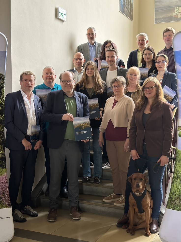 Vertreterinnen und Vertreter der Naturparke, Landtagsabgeordnete auf einer Treppe im Umweltministerium. In der Hand halten Sie den ausgedruckten Bericht.