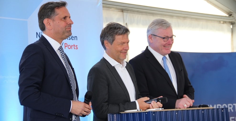Minister Lies, Minister Habeck und Minister Althusmann stehen an einem Rednerpult, im Hintergrund sieht man das Logo der Niedersachsen Ports