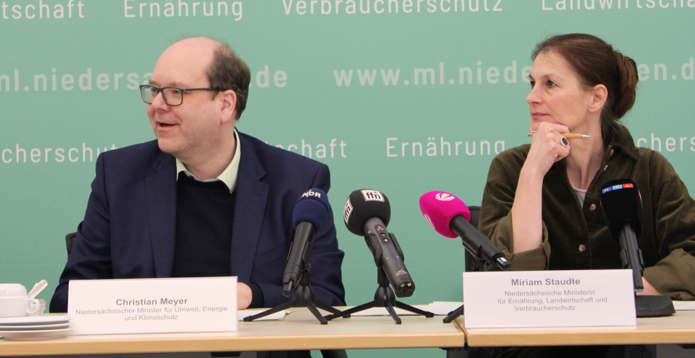 Minister Meyer und Ministerin Staudte sitzen an einem Tisch, vor Ihnen sieht man mehrere Mikrophone und Namensschilder, im Hintergrund eine Stoffwand mit den Namen des Umweltministeriums