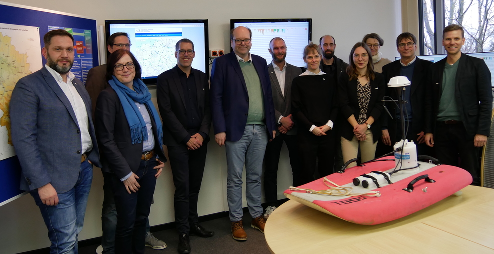 Das Team der Hochwasservorhersagezentrale des NLWKN steht mit Minister Meyer vor einem Messgerät.