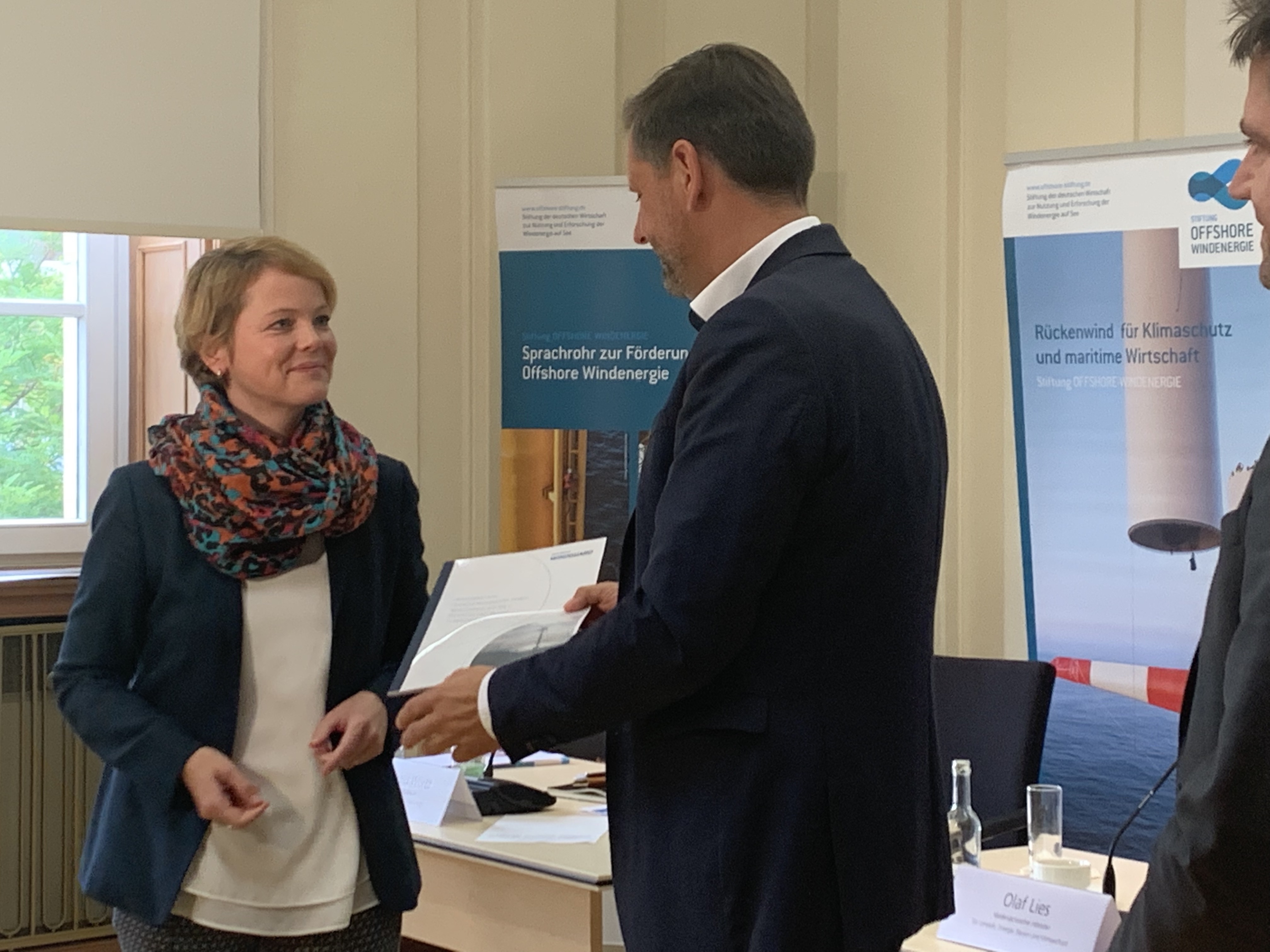 Minister Olaf Lies überreicht eine gebundene Broschüre an Stiftungsgeschäftsführerin Karina Würtz