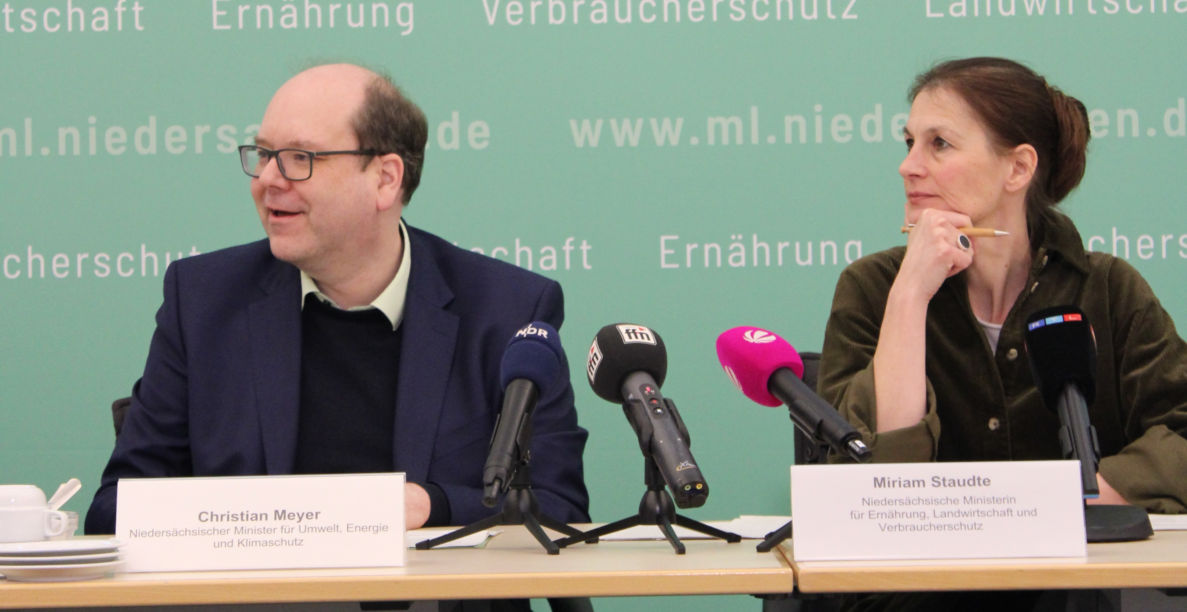 Minister Meyer und Ministerin Staudte sitzen an einem Tisch, vor Ihnen sieht man mehrere Mikrophone und Namensschilder, im Hintergrund eine Stoffwand mit den Namen des Umweltministeriums