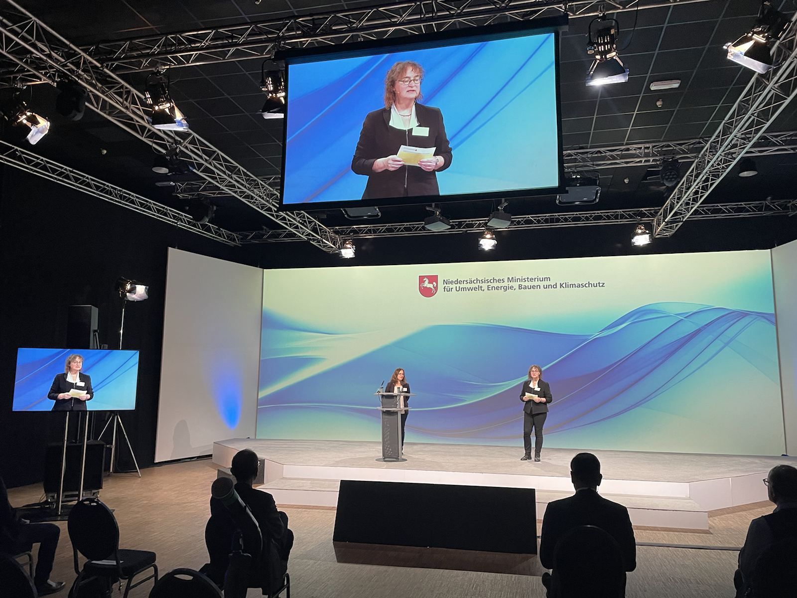 Cornelia Scupin spricht auf einer Bühne, im Hintergrund ist das Logo des Umweltministerium zu sehen