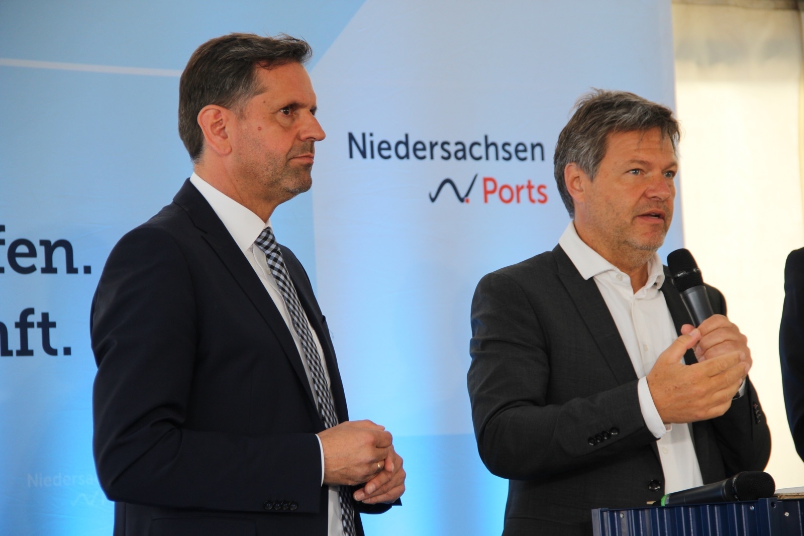 Minister Lies und Minister Habeck stehen an einem Rednerpult, im Hintergrund sieht man das Logo Niedersachsen Ports